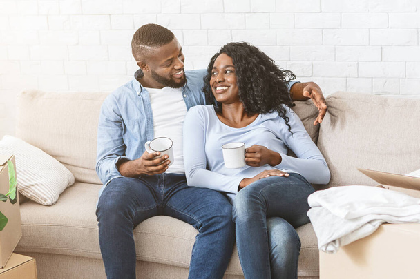 Czarna para w miłości siedzi na kanapie w nowym domu - Zdjęcie, obraz