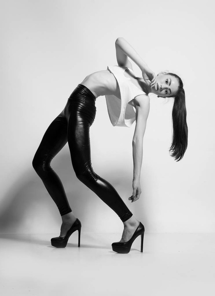Chica posando en leggings de cuero y tacones. Foto en blanco y negro
. - Foto, Imagen