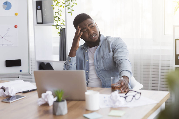 Estressado funcionário afro-americano bebendo álcool no escritório
 - Foto, Imagem