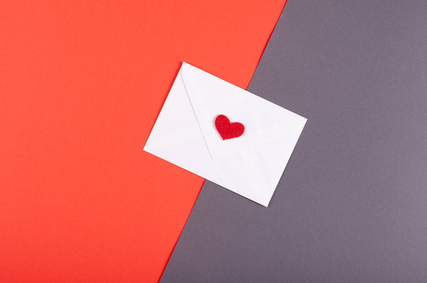Бумажный конверт с красным составом сердца на красном фоне
. - Фото, изображение