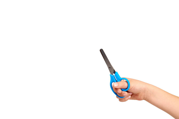 Children hand with blue little scissors, kids educational work. - Foto, afbeelding