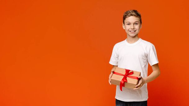 Smiling teenage boy with holiday gift box - 写真・画像