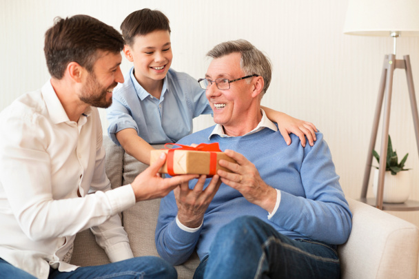 Father And Son Congratulating Grandpa Giving Birthday Gift At Home - Fotoğraf, Görsel