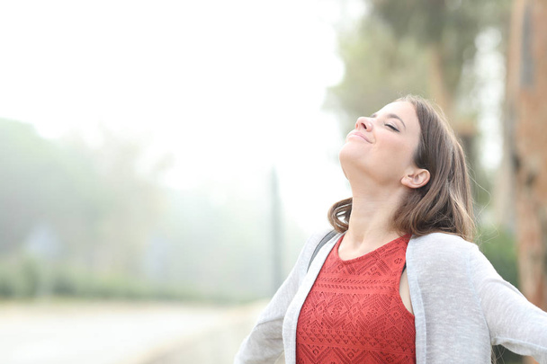 Zadowolona kobieta oddycha świeżym powietrzem w mglisty dzień - Zdjęcie, obraz
