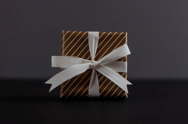 caja de regalo con nudo de lazo sobre fondo oscuro
 - Foto, imagen
