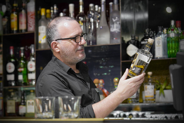 Elderly bartender male gives a glass of whiskey - 写真・画像