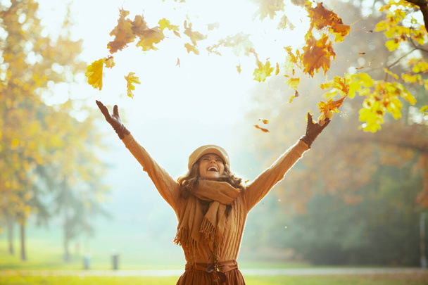 χαρούμενη γυναίκα που απολαμβάνει το φθινόπωρο και πιάνει πεσμένα κίτρινα φύλλα - Φωτογραφία, εικόνα