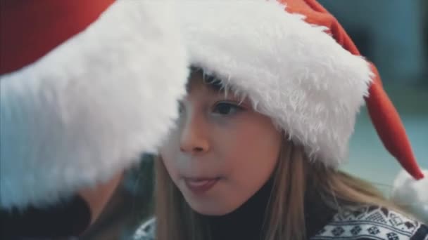4k termés videó gondolkodó gyerekek visel Mikulás kalap karácsony este, ivás forró kakaó és kíváncsi, hogy mit kapnak ajándékba. - Felvétel, videó