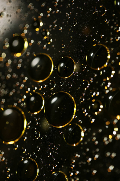 Golden oil bubbles macro on water black background with bokeh fi - Photo, Image
