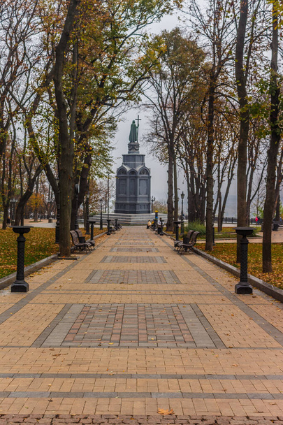 Κίεβο, Ουκρανία - 27 Οκτωβρίου 2019: Φθινόπωρο στο Κίεβο πάρκο. Άποψη μνημείου Saint Vladimir μέσω του κίτρινου φυλλώματος δέντρων στο πάρκο Vladimir και θέα του ποταμού Δνείπερου στο αστικό πάρκο Volodymyrska Hill - Φωτογραφία, εικόνα