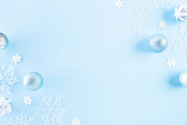 クリスマスの背景概念。薄青のパステルを背景に雪の結晶を持つクリスマスボールのトップビュー. - 写真・画像