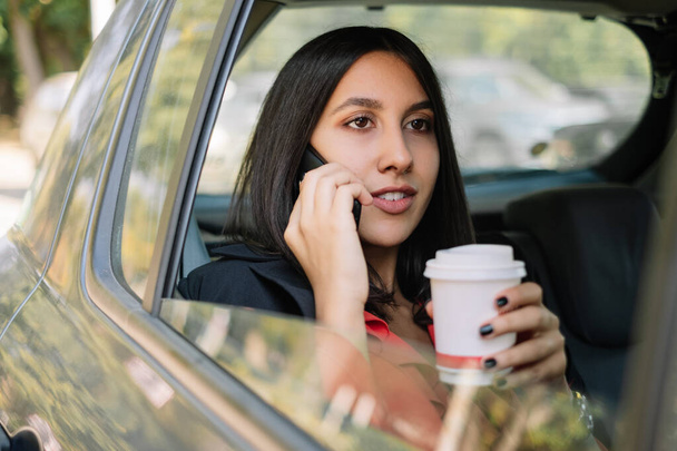 Woman with cup of coffee in car - 写真・画像