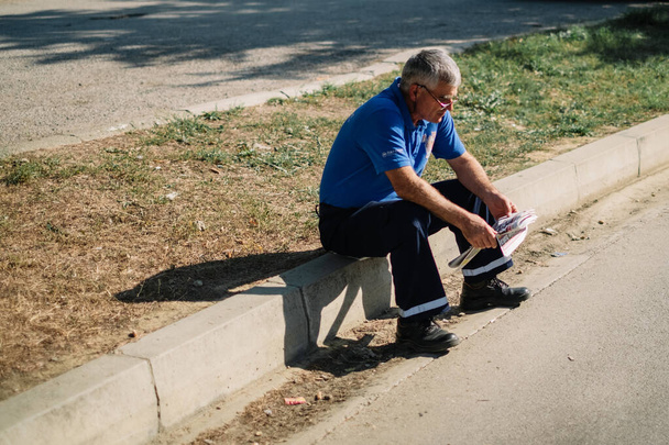 Egy férfi ül az utcán, és újságot olvas. - Fotó, kép