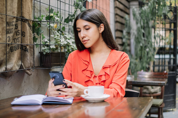 Brunette woman using her phone while having a coffee - Photo, Image