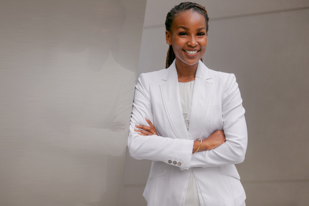 Africano americano mulher de negócios sorrindo confiantemente, alegre, realizado, orgulhoso, bem sucedido, na construção do local de trabalho financeiro
 - Foto, Imagem