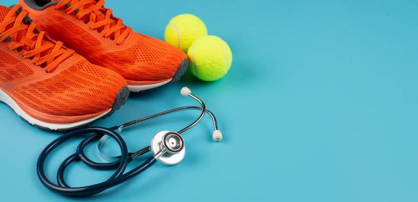 Orange sports shoes and stethoscope on the blue background. Conc - Фото, изображение