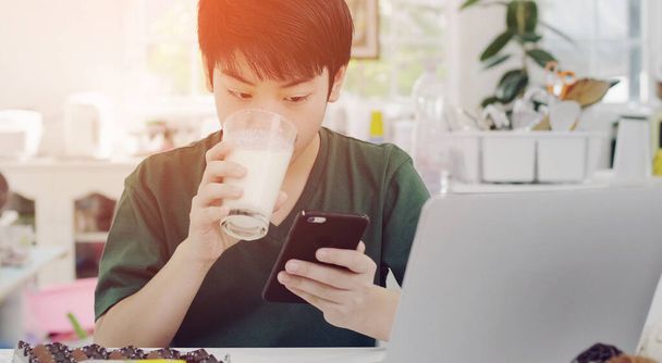 Asian young boy using smartphone applications, while drink organ - Foto, imagen