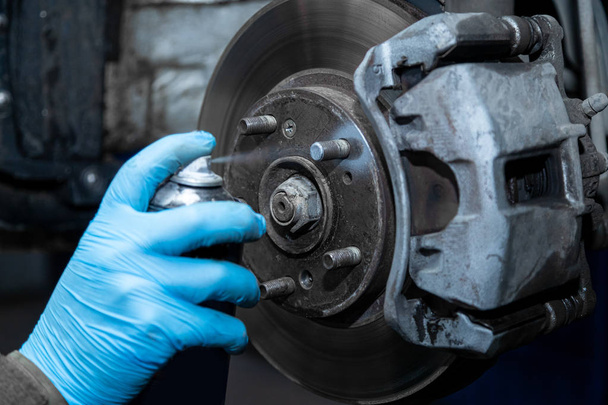 Close-up Workshop worker in protective gloves lubricates wheel studs, brake repair. Work at the tire workshop - Φωτογραφία, εικόνα