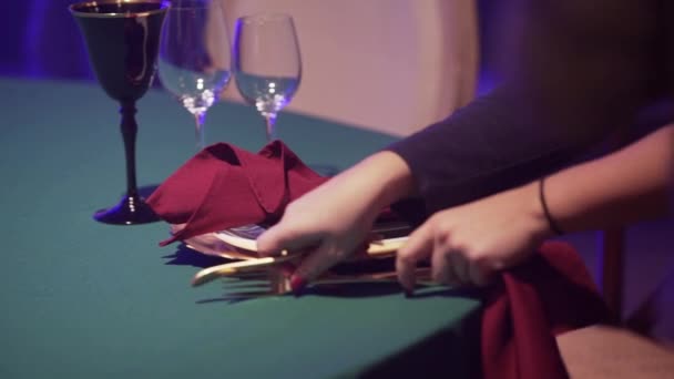 Γυναικεία χέρια σερβίρουν τραπέζι με πράσινο τραπεζομάντηλο και ποτήρια στο εστιατόριο - Πλάνα, βίντεο