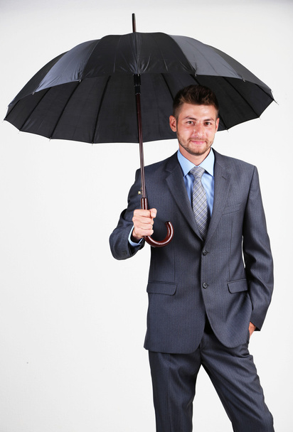 Businessman with umbrella. on gray background - Zdjęcie, obraz