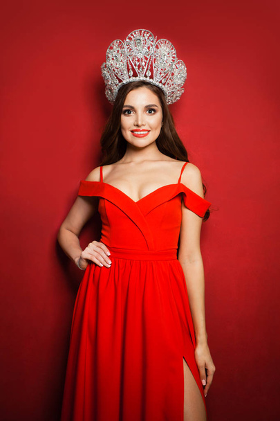 Gorgeous woman fashion model wearing red dress and diamond crown - Foto, afbeelding