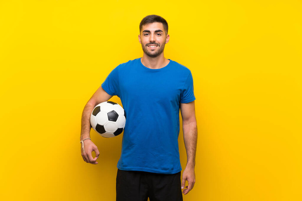 Giovane giocatore di calcio bello uomo oltre isolato muro giallo sorridente molto
 - Foto, immagini