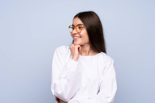 Mladá žena nad izolované modré pozadí s brýlemi - Fotografie, Obrázek