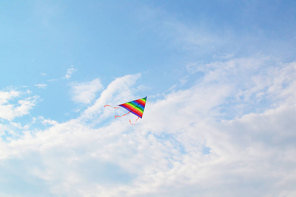 A rainbow kite flying against a blue sky and clouds using for the way to success and milestone concept. - Foto, Imagen