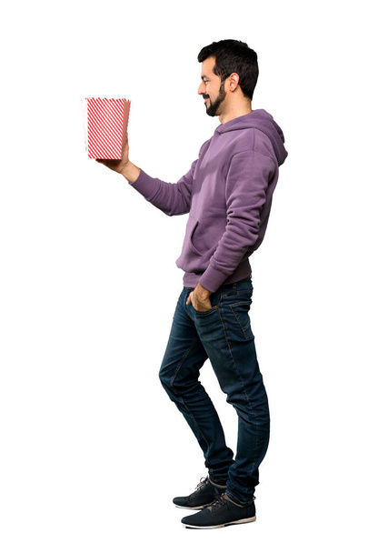Full-length shot of Handsome man with sweatshirt eating popcorns over isolated white background - Fotografie, Obrázek