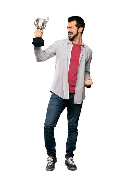 Full-length shot of Handsome man with beard holding a trophy over isolated white background - Foto, Bild
