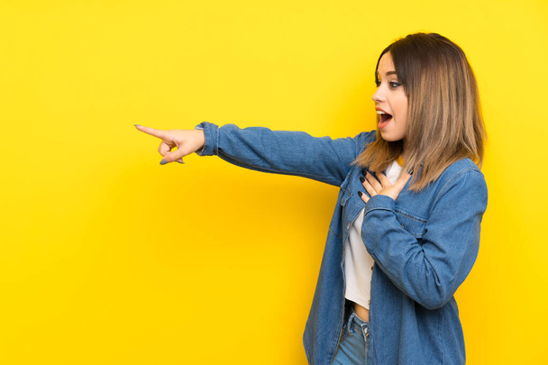 Young woman over yellow background pointing finger to the side - Foto, Bild