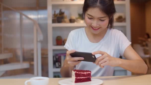 Blogger Asiático amigável mulheres influenciador comer bolo no café da noite. Menina bonita feliz relaxar divertido usando tecnologia telefone celular tirar uma foto de seu upload de alimentos nas mídias sociais no campus universitário
. - Filmagem, Vídeo