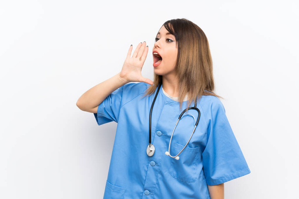 junge Krankenschwester schreit mit weit geöffnetem Mund über die weiße Wand - Foto, Bild