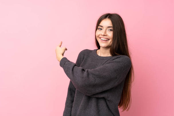 Young woman over isolated pink background pointing back - Photo, Image
