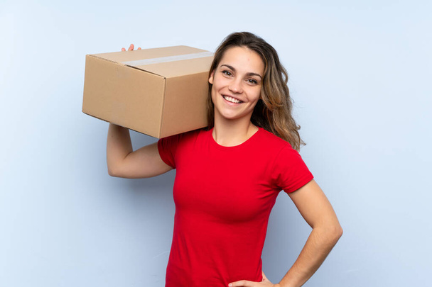 Νεαρή ξανθιά γυναίκα κρατώντας ένα κουτί για να το μετακινήσετε σε μια άλλη τοποθεσία - Φωτογραφία, εικόνα