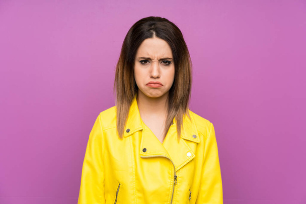 junge Frau über lila Hintergrund traurig - Foto, Bild