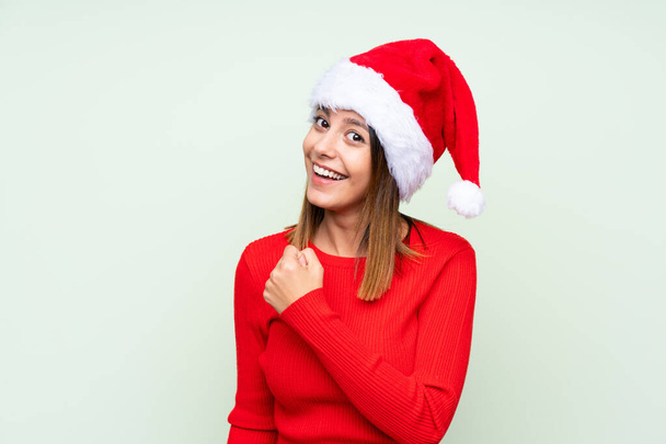 Girl with christmas hat over isolated green background celebrating a victory - 写真・画像
