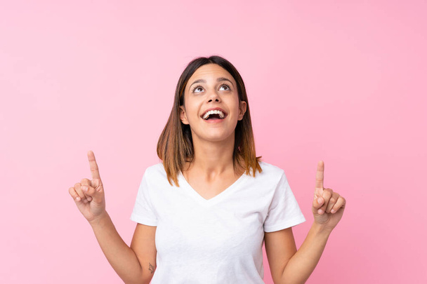 Young woman over isolated pink background surprised and pointing up - Photo, Image