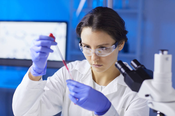 Retrato de una joven científica que prepara una muestra de análisis de sangre con gotero mientras trabaja en un laboratorio médico, espacio para copiar
 - Foto, Imagen