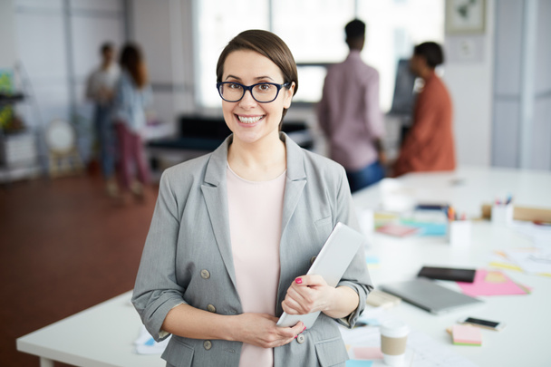 Taille omhoog portret van succesvolle zakenvrouw glimlachend op de camera en het houden van digitale tablet terwijl staan in modern kantoor, kopieer ruimte - Foto, afbeelding