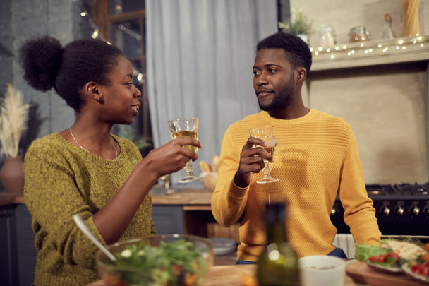 taille omhoog portret van jonge Afro-Amerikaanse paar drinken wijn terwijl u geniet van diner thuis, kopieer ruimte - Foto, afbeelding