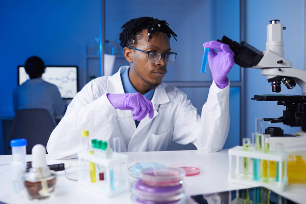 Портрет юного афро-американського чоловіка, який тримає зразки пробірки під час роботи над медичними дослідженнями в лабораторії, копіювання простору - Фото, зображення