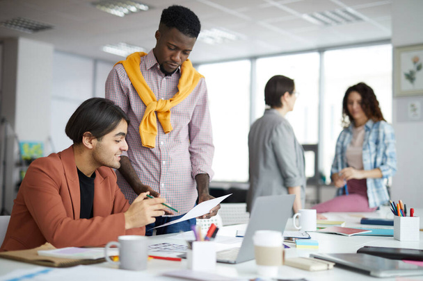 Різноманітна команда з творчої молоді обговорює стартап-проект в сучасному офісі, зосереджується на двох етнічних чоловіків на передньому плані, копіює простір
 - Фото, зображення