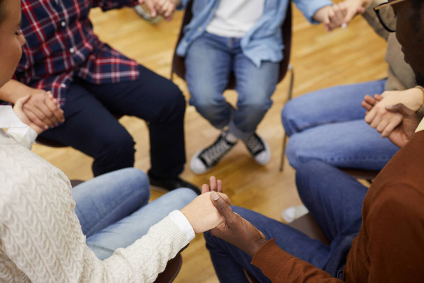 High angle closeup of unrecognizable people sitting ion circle and holding hands during support group meeting, cpy space - Photo, Image