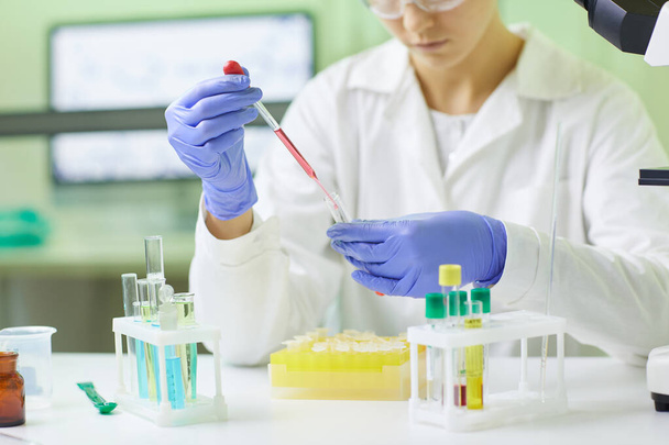 Close-up de jovem cientista preparando amostra de teste de sangue usando conta-gotas enquanto trabalhava em laboratório médico, espaço de cópia
 - Foto, Imagem