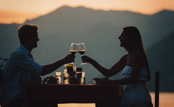 Couple is having a private event dinner on a tropical beach during sunset time. Honeymoon travel concept - Фото, изображение