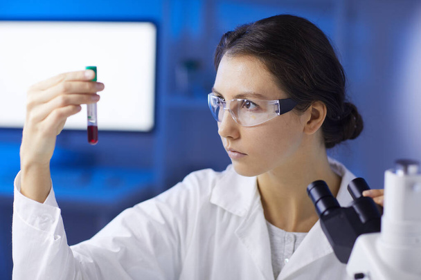 Retrato de una mujer joven sosteniendo una muestra de sangre mientras hace investigación médica en laboratorio, espacio para copiar
 - Foto, Imagen
