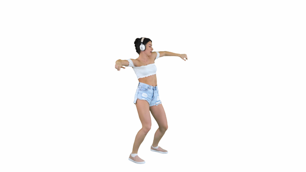 Modelo femenino caucásico en audífonos saltando, expresando emociones felices escuchando música sobre fondo blanco
. - Imágenes, Vídeo