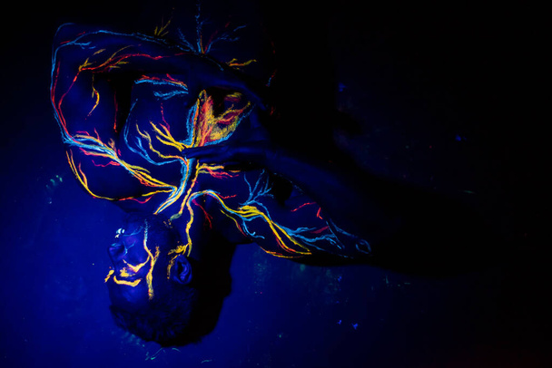 UV patterns body art of the circulatory system on a mans body. On the chest of a muscular athlete, veins and arteries are drawn with fluorescent dyes. The bodybuilder straightened the biceps - Zdjęcie, obraz