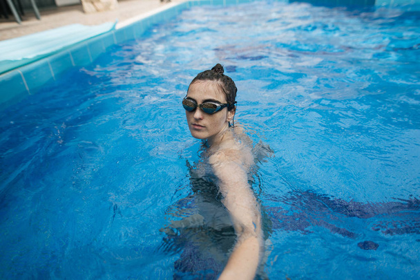 young woman swims in sports glasses in the pool - Foto, imagen